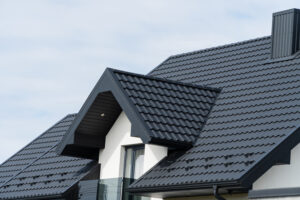 A beautiful modern house is covered with black metal tiles. Roofing of metal profile wavy shape